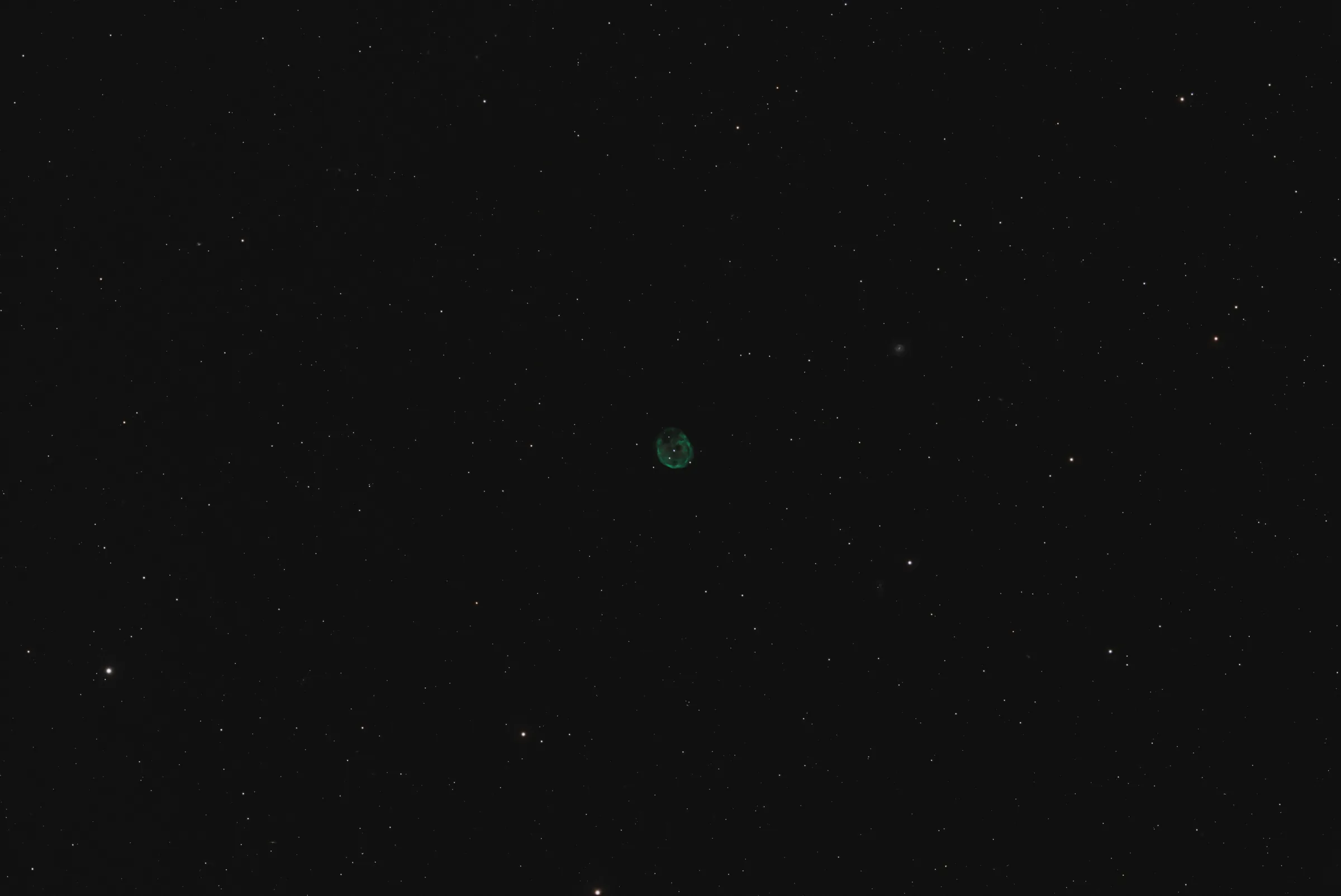The Skull Nebula, a faint green planetary nebula in a sparse star field.